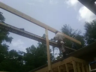 Carpenter setting a ridge beam over a new addition frame — Ice Dam Removal by Roofing Brothers in Vian