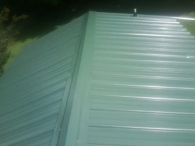New green metal panels meeting at the ridge of a roof — Flat Roof Repair work by our crew in Vian