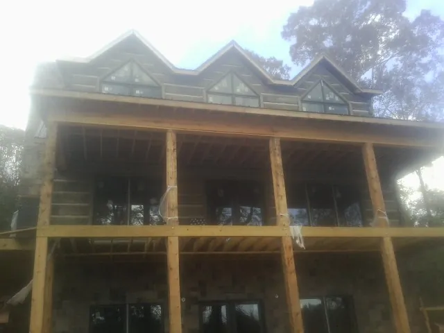 Dormers and porch framing on a large log home under construction — Roof Coating work by our crew in Vian