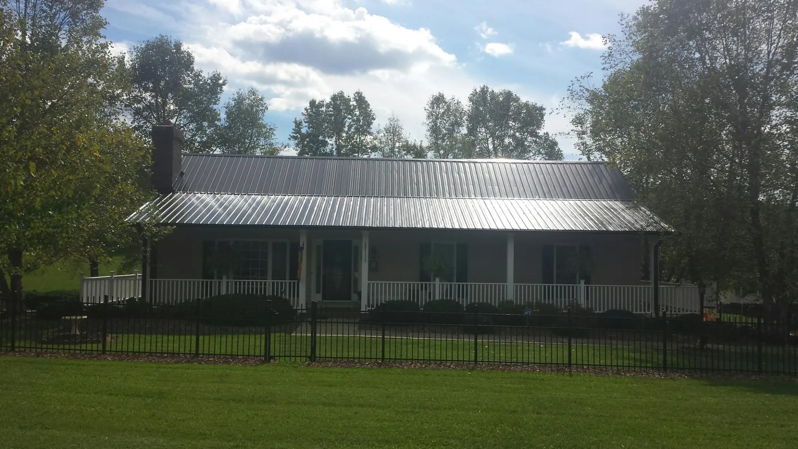 Gray metal roof on a brick ranch with a full width front porch — Gutter Guard Installation work by our crew in Vian