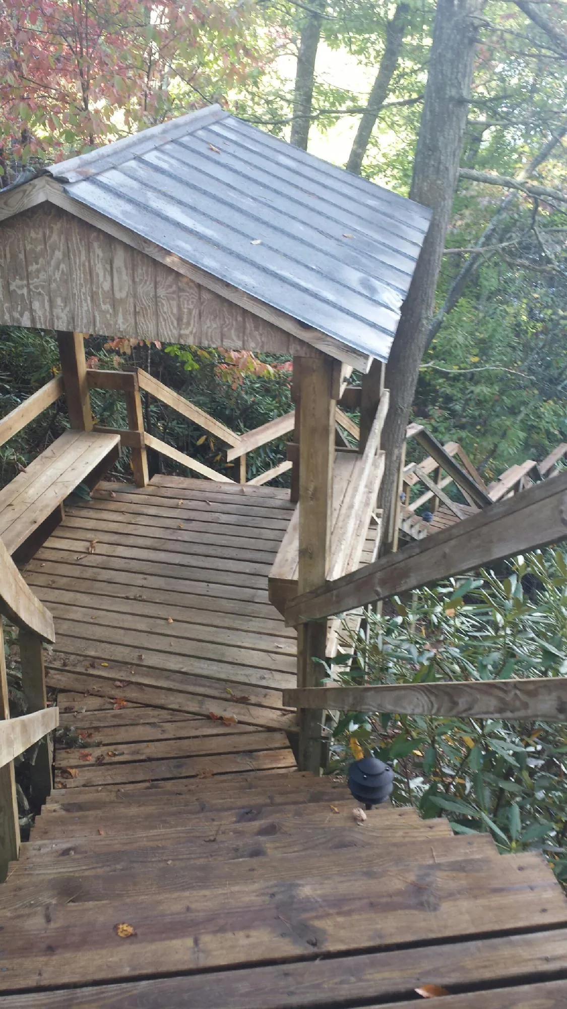 Metal roofed shelter over wooden steps on a wooded walkway — Skylight Repair & Installation work by our crew in Vian