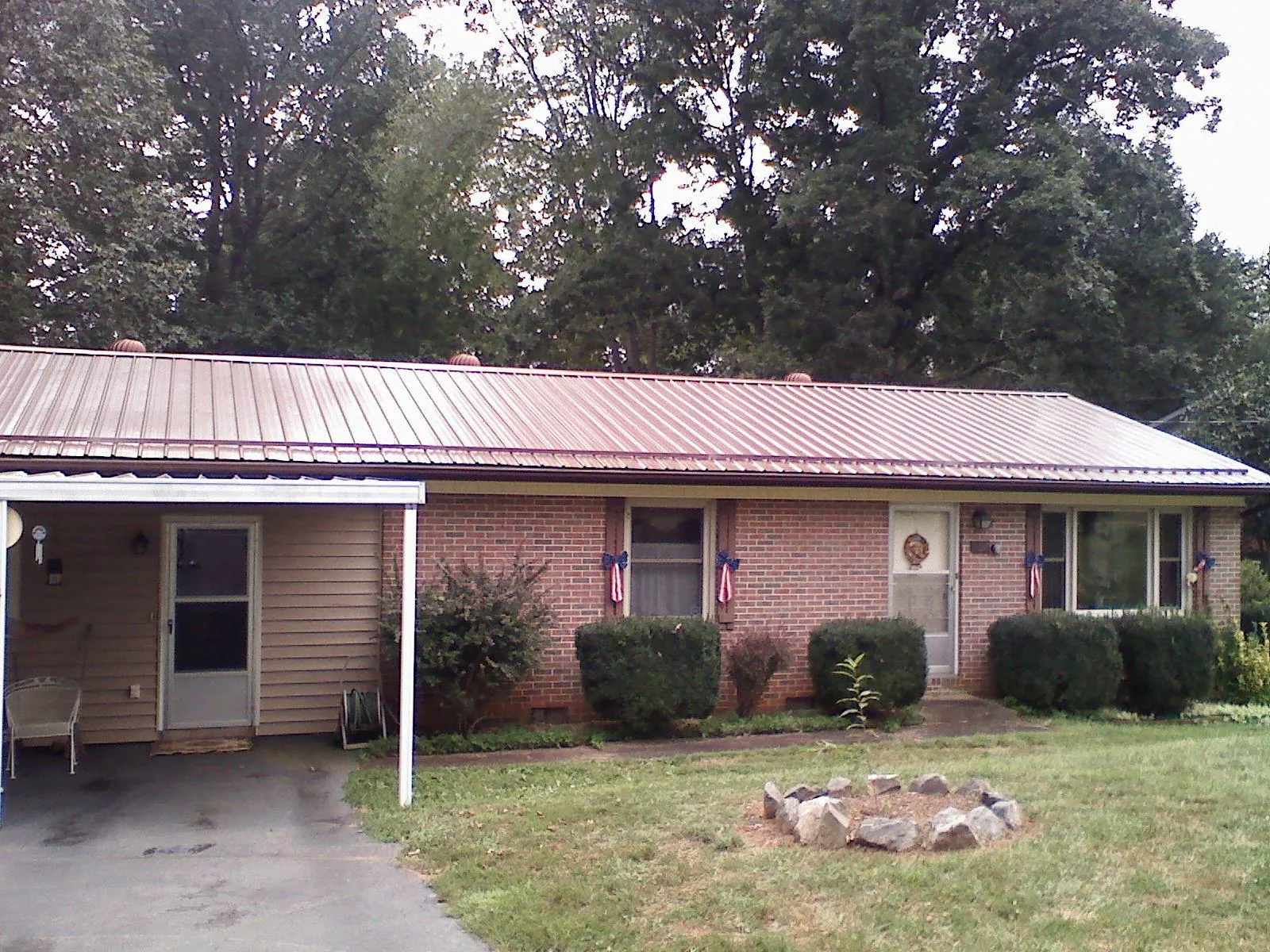Bronze metal roof and carport on a brick ranch home — Roof Repair work by our crew in Vian