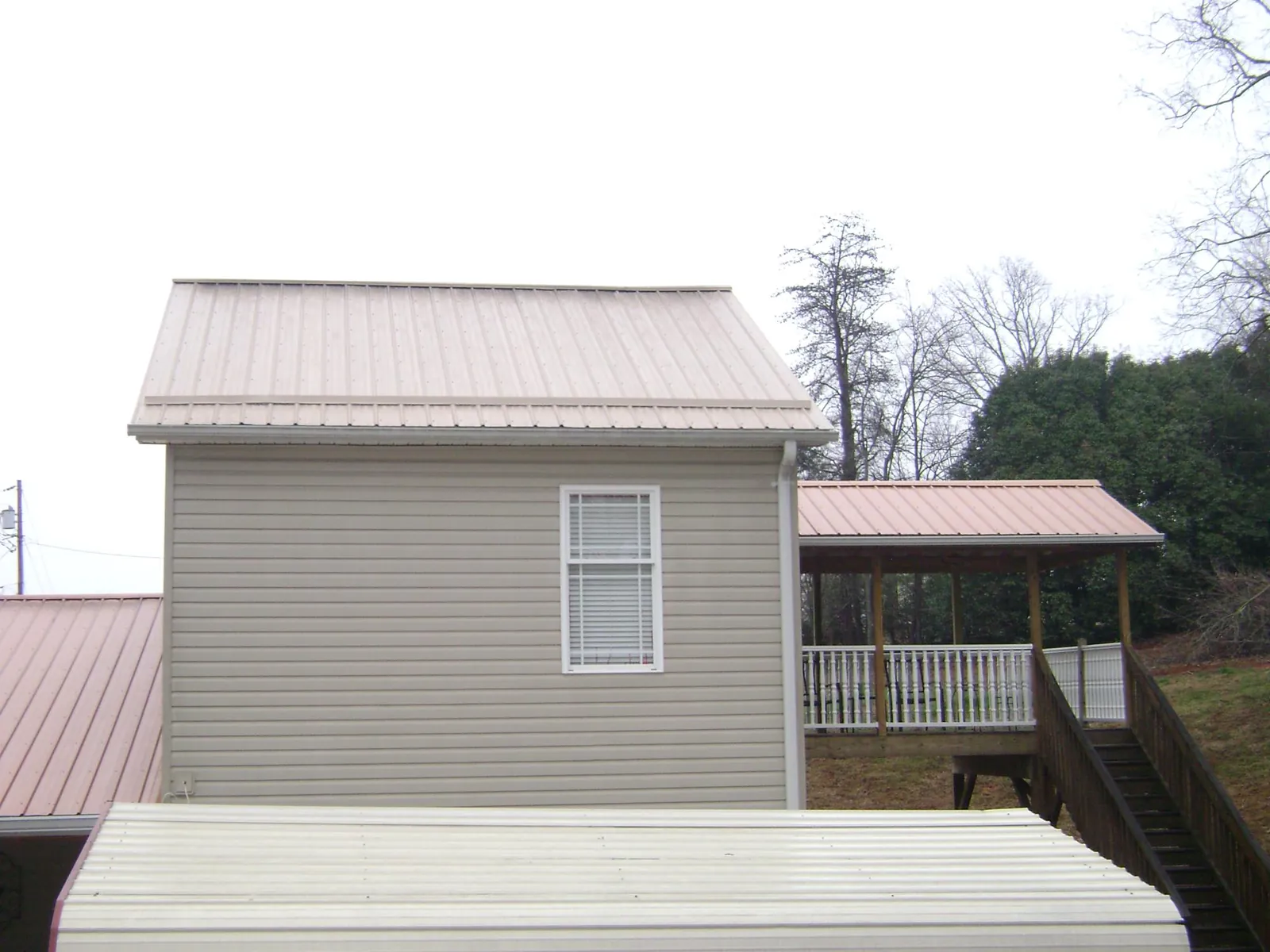 Tan metal roofs on a two story addition and attached porch, from a Roof Replacement job in Vian